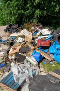 Illegally disposed waste, car tyres, building rubble, household waste, clothing, on a path next to