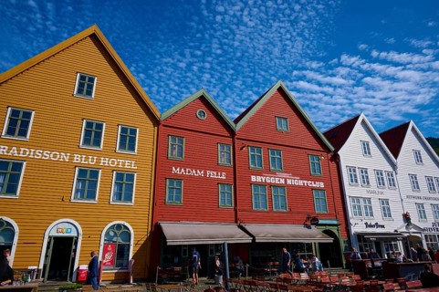 Traditional wooden houses under a blue sky with pitched roofs and multiple windows in a sunny old