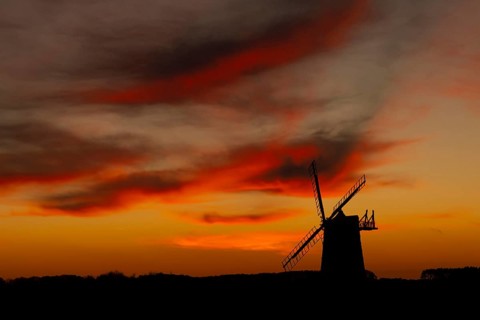 Windmill silhouette at sunset with a red sky and clouds, Burnham Ovary Staithe, Norfolk, England,
