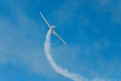 Stunt aerobatic plane performing stunts in blue sky with smoke trail. Concept of teamwork,