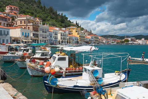 Historic coastal town with mooring boats on the water and colourful facades under a cloudy sky,