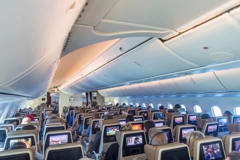 Etihad airline aircraft, interior, rows of seats with passengers. Boeing 787 aircraft on a flight