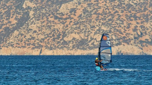 Windsurfer with view of rocky coast, clear blue water, windsurfer, Meltemi windsurfing area, Devils
