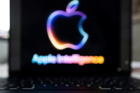 Blurred Apple Intelligence logo in bright neon colours on a Macbook with illuminated keyboard,