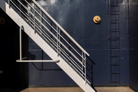 White painted metal stairs and black ladder against blue metal wall on a cruise ship, La Spezia,