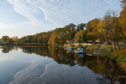 Idyllic river landscape in autumn with trees, boats and reflections in the water, River Mulde,