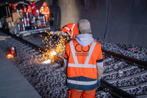 Observing workers watching welding work with spark spraying in the tunnel, rail welding, track
