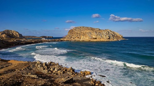 Rocky coastal landscape with blue sky and crashing waves, Acropolis Hill, Arkasa, West Coast,