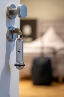Symbolic image of a hotel, key inserted in the door of a hotel room, analogue lock