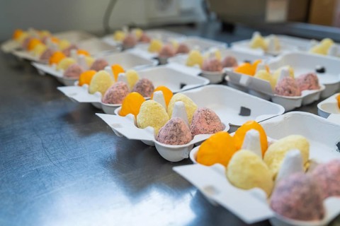 Colourful egg creations in packaging on a metal table, neatly lined up, Easter baking and chocolate