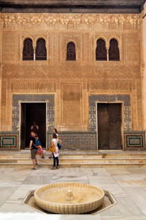 Patio del Cuarto Dorado with tourists, arabesque Moorish architecture, arched windows and