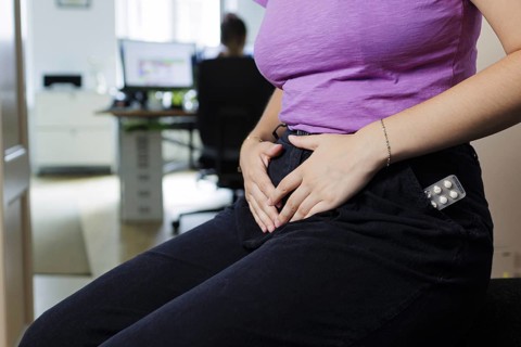 A woman has abdominal pain while working in the office. Berlin, 08.08.2024