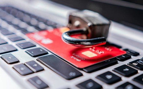 Padlock on top of credit card on laptop keyboard. Open padlock with credit card on keyboard.