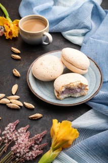 Meringues cakes with cup of coffee on a black concrete background and blue linen textile. Side