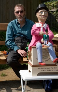 Man operating a traditional wooden jig doll dancer during a country folk event at Shottisham,