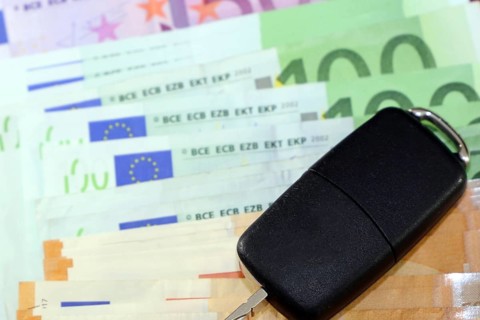 Euro banknotes and car keys as a symbol for car costs