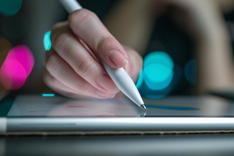 Close up of female hand writing with white pen on computer tablet. KI generiert, generiert, AI