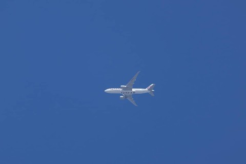 Boeing 777 jet aircraft of Qatar air cargo in flight across a blue sky, England, Unird Kingdom