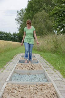 Woman walking barefoot over glass gravel and bottle corks, barefoot path Tilbeck Abbey, Havixbeck,