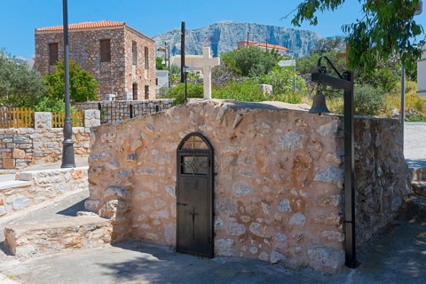 Rustic stone building in a Mediterranean landscape under a blue sky, Church of Agios Nikolaos,
