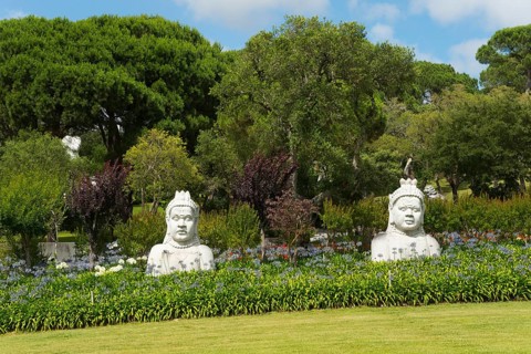 Two Buddha statues in a green, peaceful garden with numerous trees and bushes, Bacalhôa, Bacalhoa