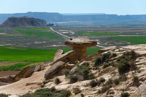 Landscape with unique rock formations and a green valley under a clear blue sky, Bardenas Reales