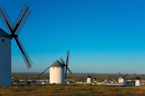 Windmills overlook a small village under a clear sky, Campo de Criptana, Ciudad Real province,