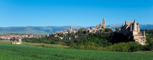 Panoramic view of a historic city with a cathedral and a castle surrounded by green fields and