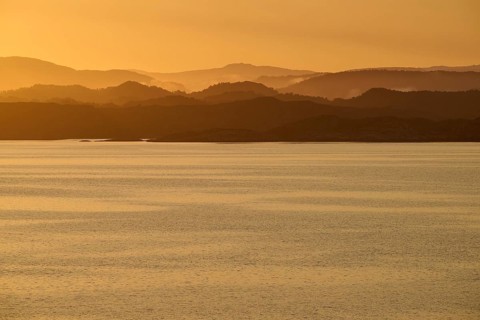 Calm atmosphere over the sea, hills and an orange sunrise, autumn, Bergen, North Sea, Norway,