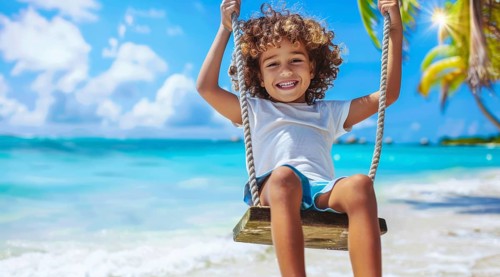 Happy smiling children on a swing at sea shore on family Caribbean vacation near the ocean beach,