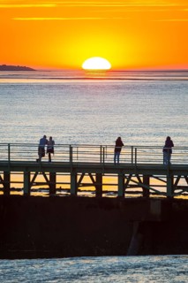 Silhouettes of several people on the pier Freilaufkanal, couple and single persons watch from a