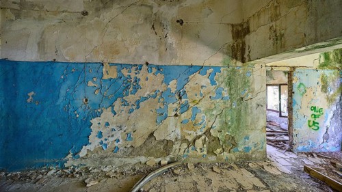 Blue and white peeling wall in a dilapidated room with partially visible graffiti, Lost Place,