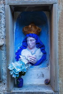 Religious blue and white with golden crown female with praying hands sculpture and silk flowers in