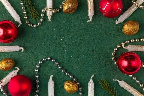 Frame made of Christmas decorations, candles, baubles, nuts on a green background, copy room