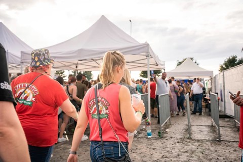 People in red T-shirts walk past white tents at a festival, Malleparty Böblingen, Germany, Europe