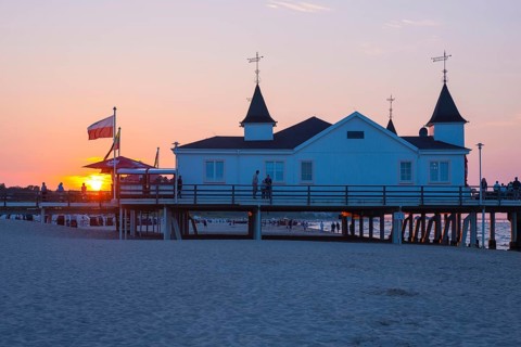 People strolling on a pier with buildings in the sunset, clear, blue, cloudless sky, pier Ahlbeck