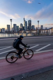 Skyline of the city centre of Frankfurt am Main, cyclist on the Ignatz-Bubis-Bridge, dusk, river