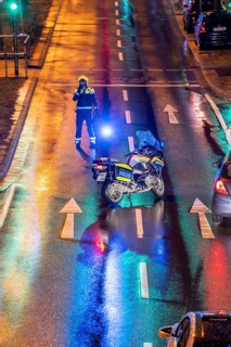 Policeman with motorbike, in rainy weather, blocking a road, police motorbike with blue light