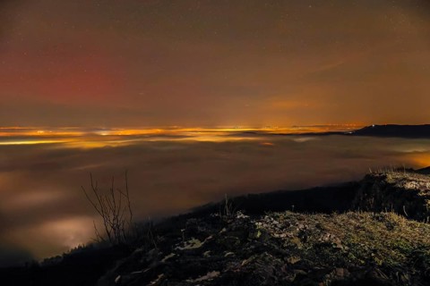Firework lights under the sea of fog. New Year's Eve fireworks 2024 and a little red Aurora