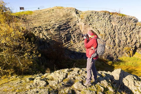 Photographer with camera and rucksack taking pictures at Hirtstein, Marienberg, Saxony, Germany,