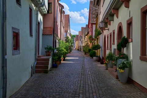 Idyllic narrow alley with cobblestones and traditional houses decorated with flowers under a bright