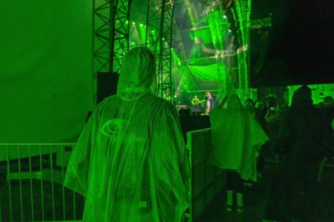 Person in green rain poncho at a night concert with green stage lighting, Klostersommer, Calw