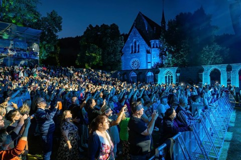 Large crowd at a night concert in front of a church, stage illuminated in blue, Klostersommer, Calw