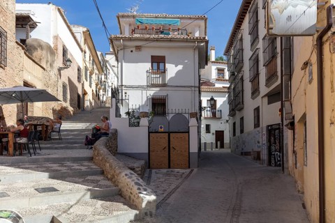 Sunny street with traditional buildings and a café, peaceful atmosphere, Granada