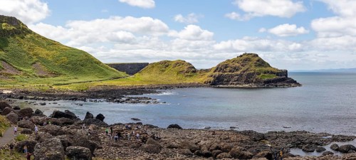 Coastal landscape with green cliffs and rocks by the sea under a blue sky, Giant Causeway