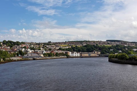 View over the river to the city with houses and blue sky, Londonderry