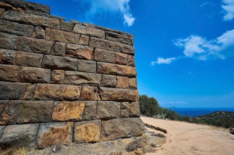 Ancient ruined wall in an arid landscape with a view of the sea and a clear blue sky, Palaiokastro,