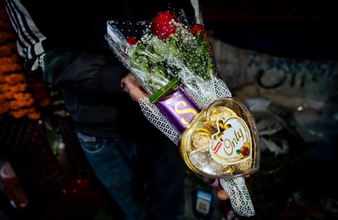 Vendor shows a rose and chocolate bouquet in a street flower shop, on the occasion of Valentines