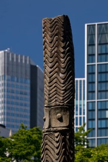 Stele made of carved wood from Papua New Guinea at the Weltkulturen Museum in front of skyscrapers,