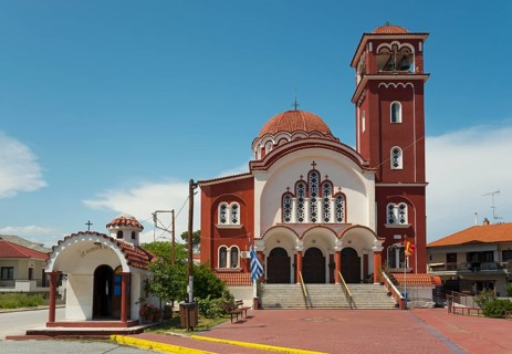 A Greek Orthodox church with a red roof and bell tower under a clear blue sky, Church of St